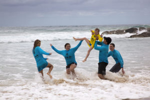 surf lifesaver volunteers in the waves with a small boy