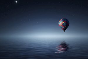 hot air balloon over water at night with stars