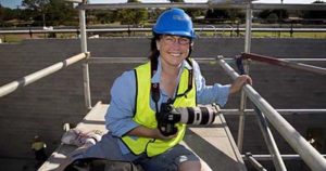 Photographer with camera high up on construction site gantry