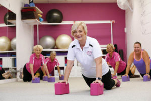 Pilates teacher demonstrating pose with midlife clients