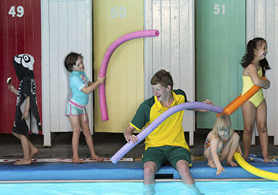 Children playing at a pool with pool noodles